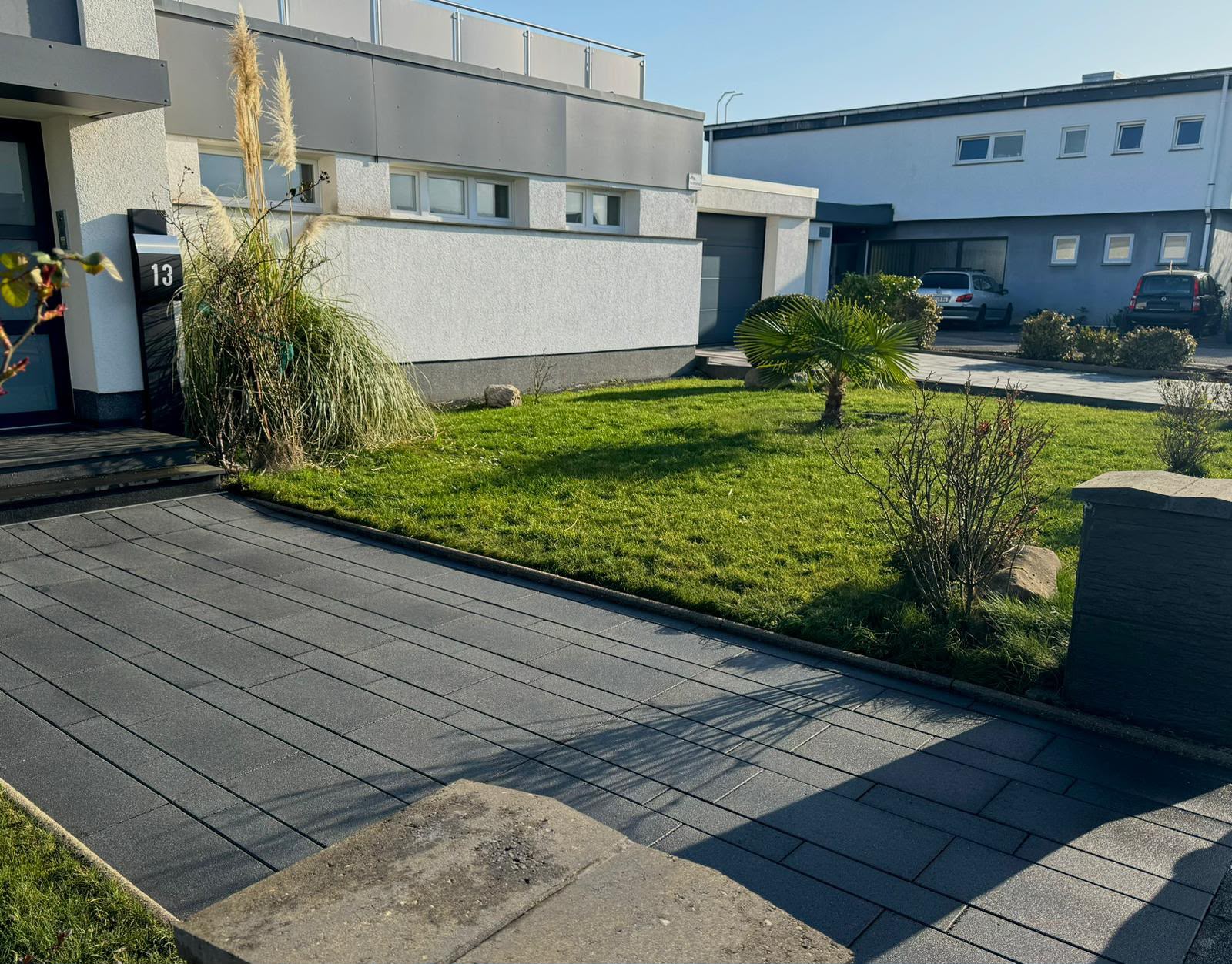 Mitarbeiter schneidet eine Hecke mit einer Heckenschere auf einem Gewerbegrundstück
